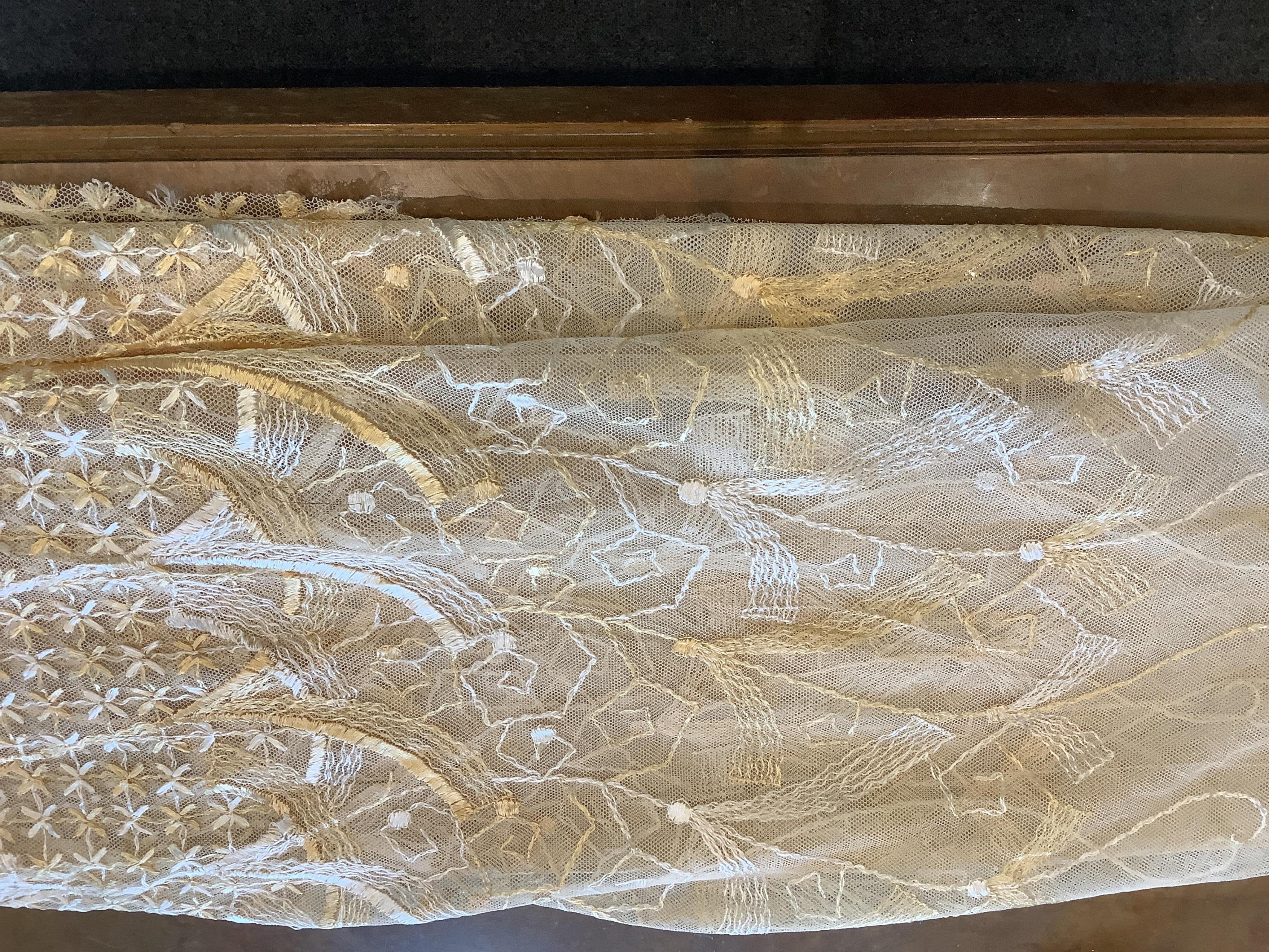 A French Art Deco wide silk yellow and cream embroidered net curtain, bordered at the bottom with yellow silk fringing. Approximately 560cm wide x 170cm long (not including fringing)., Condition - the curtain may need re